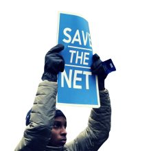 A photograph of a person holding a sign that says "Save the Net"