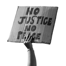 A photograph of a person holding a sign that says "No Justice No Peace"