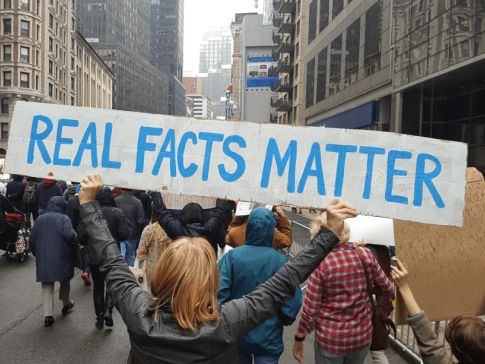 Protester holding a sign reading "Real Facts Matter"