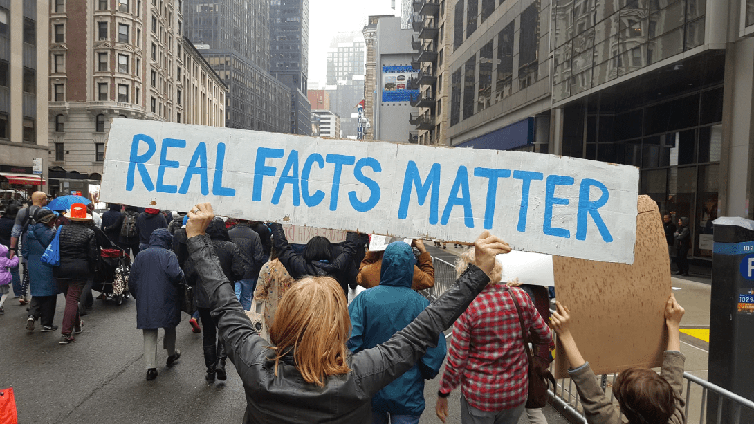 Protester holding a sign reading "Real Facts Matter"